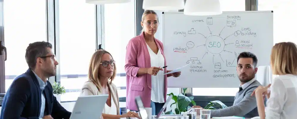 woman standing in front of a white board, directing a meeting